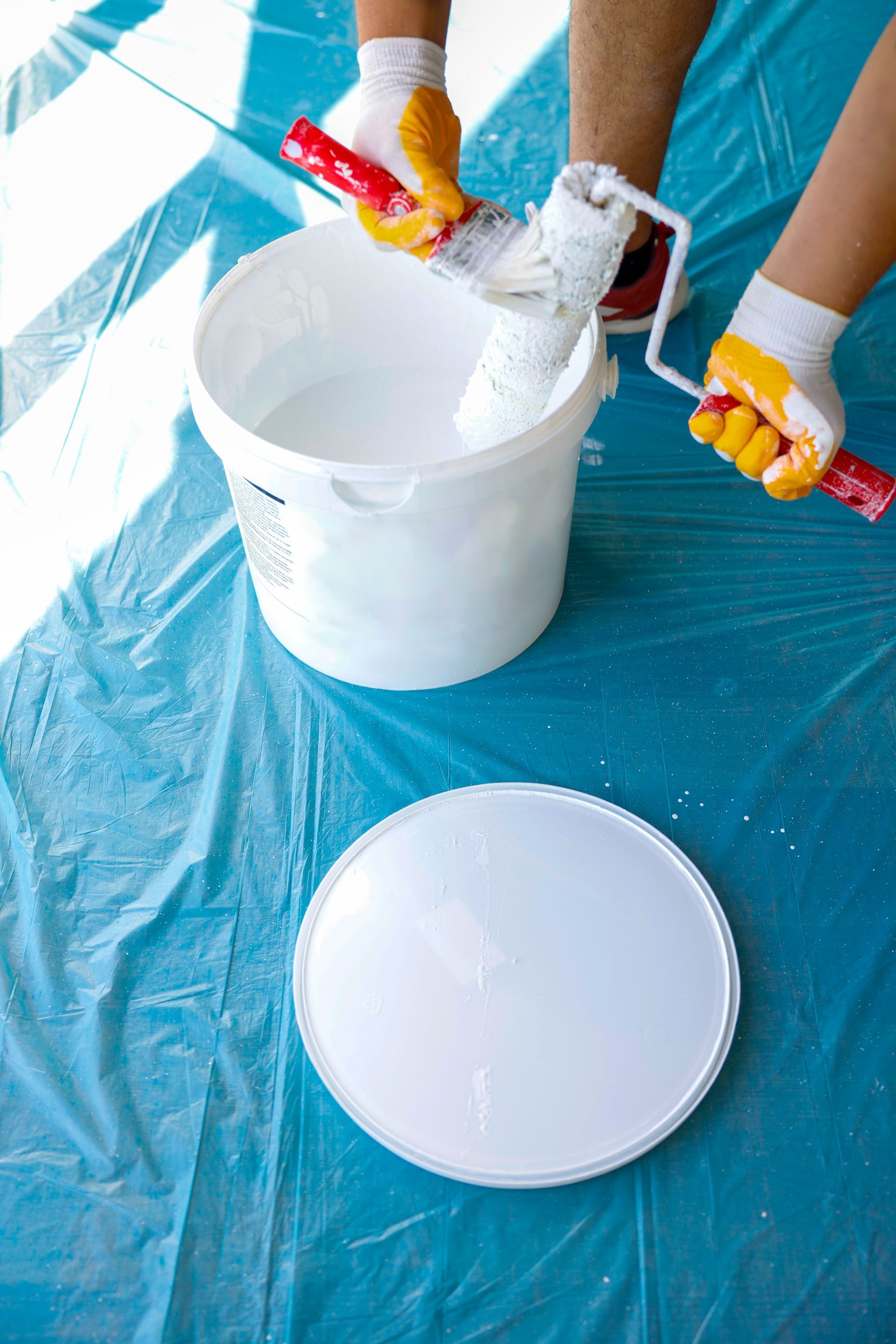 A man wearing a mask and gloves is holding a bag of dirt in a greenhouse.