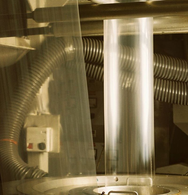 A plastic bag filled with potatoes and carrots on a wooden table.