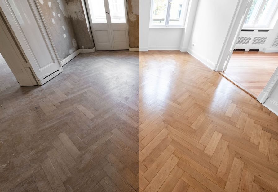 Empty room with herringbone wood floor, white walls, and windows letting in daylight