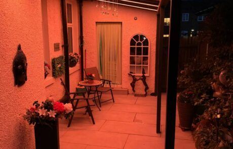 A patio with a table and chairs is lit up at night.