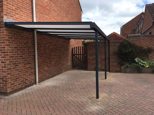 A carport is attached to the side of a brick building.