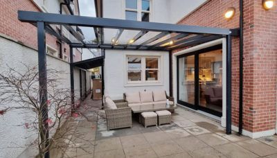 A patio with a couch and chairs under a canopy.