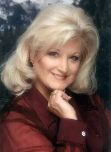 A woman with blonde hair is wearing a red shirt and smiling for the camera.