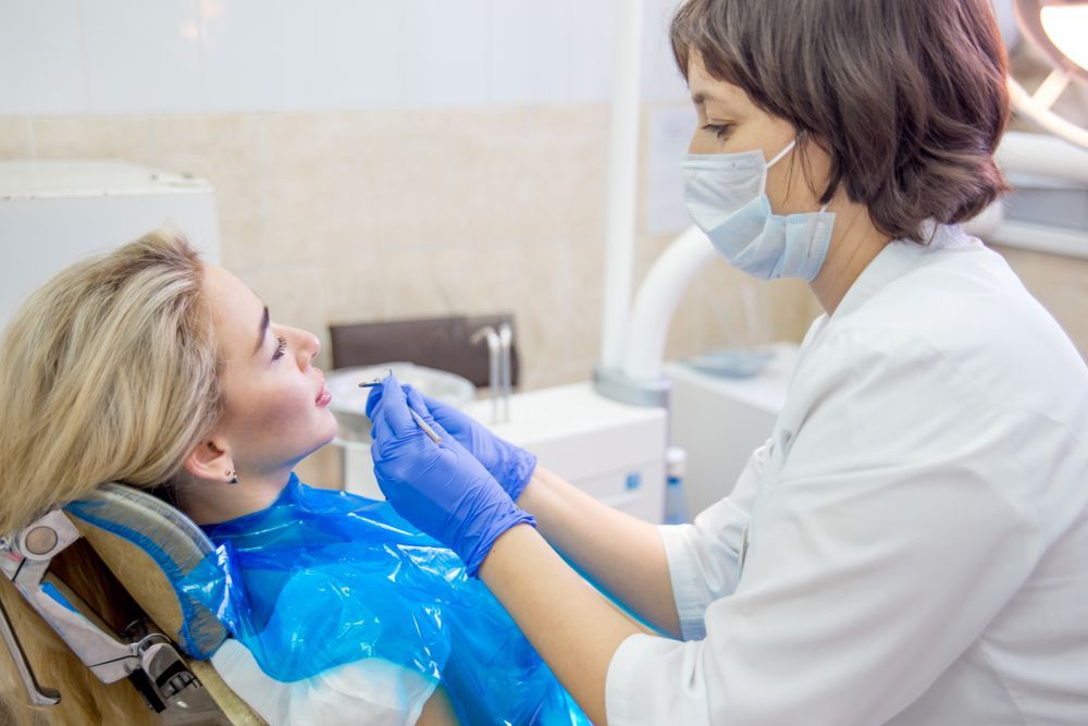 Close-up view of teeth in a mouth, some with white fillings, pink gums and tongue.