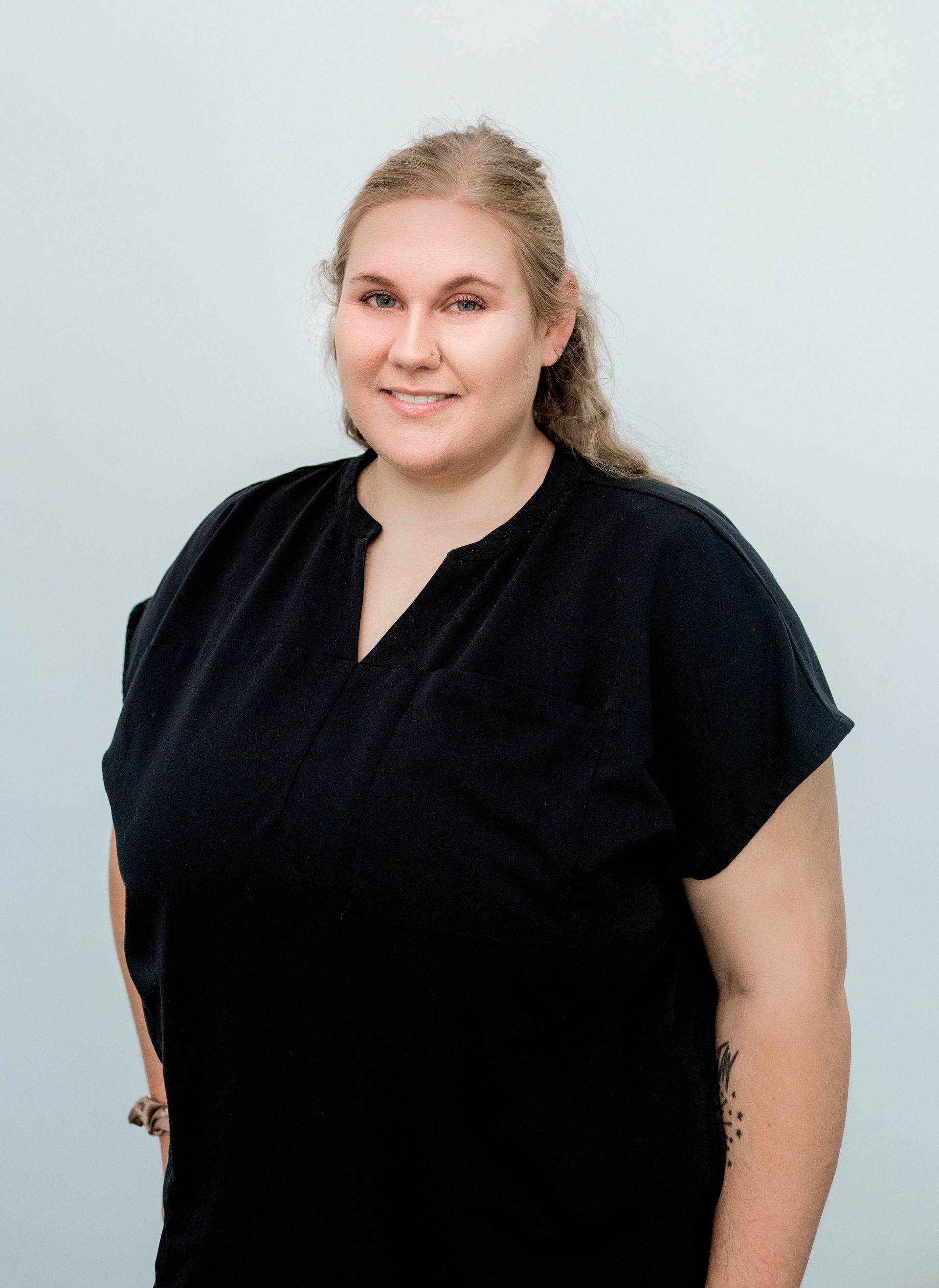 Woman with fair skin and curly blonde hair in a black shirt smiles at the camera.
