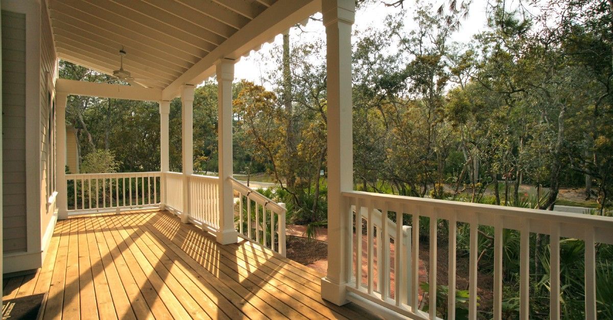 A covered porch with the sunlight streaming in and highlighting the wooden boards.