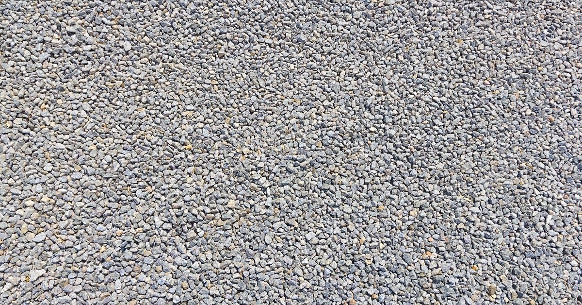 A close-up of tightly packed, small gray gravel stones with irregular shapes, subtle brown tones, and a dry, textured surface.