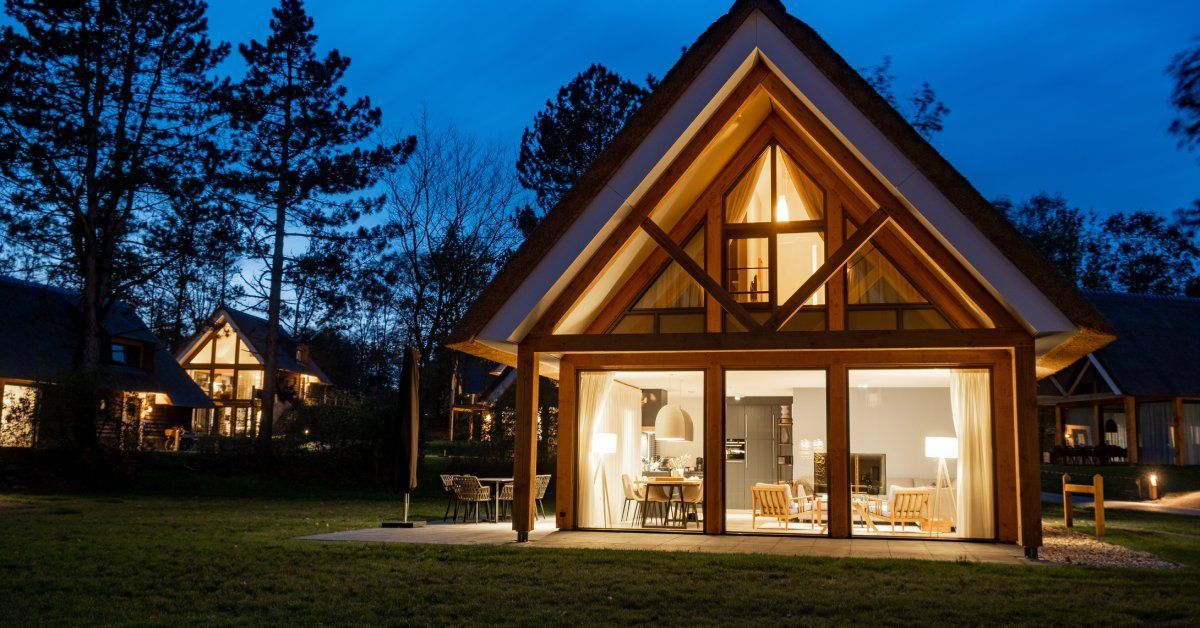 The exterior of a farmhouse-style home with a peaked roof at night.