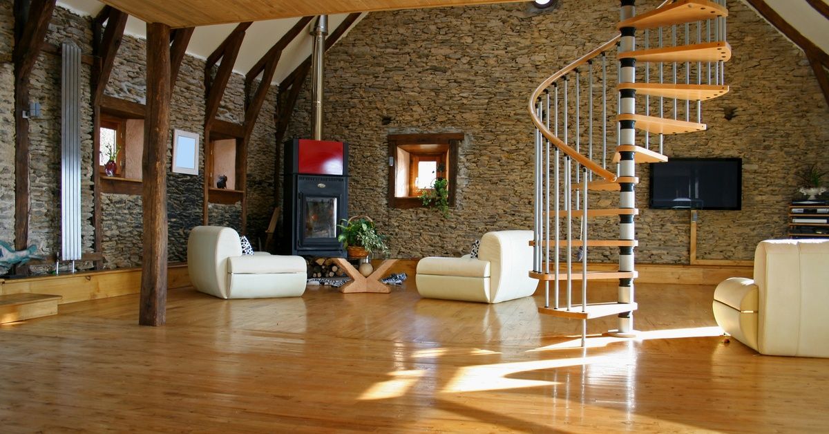 A large open space with a high ceiling within a home. There is a spiral staircase, furniture, and a second level.