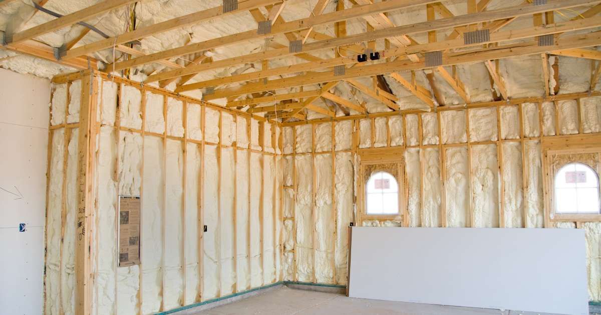 A home's interior is lined with spray foam insulation. The lack of construction exposes the wooden beams and windows.