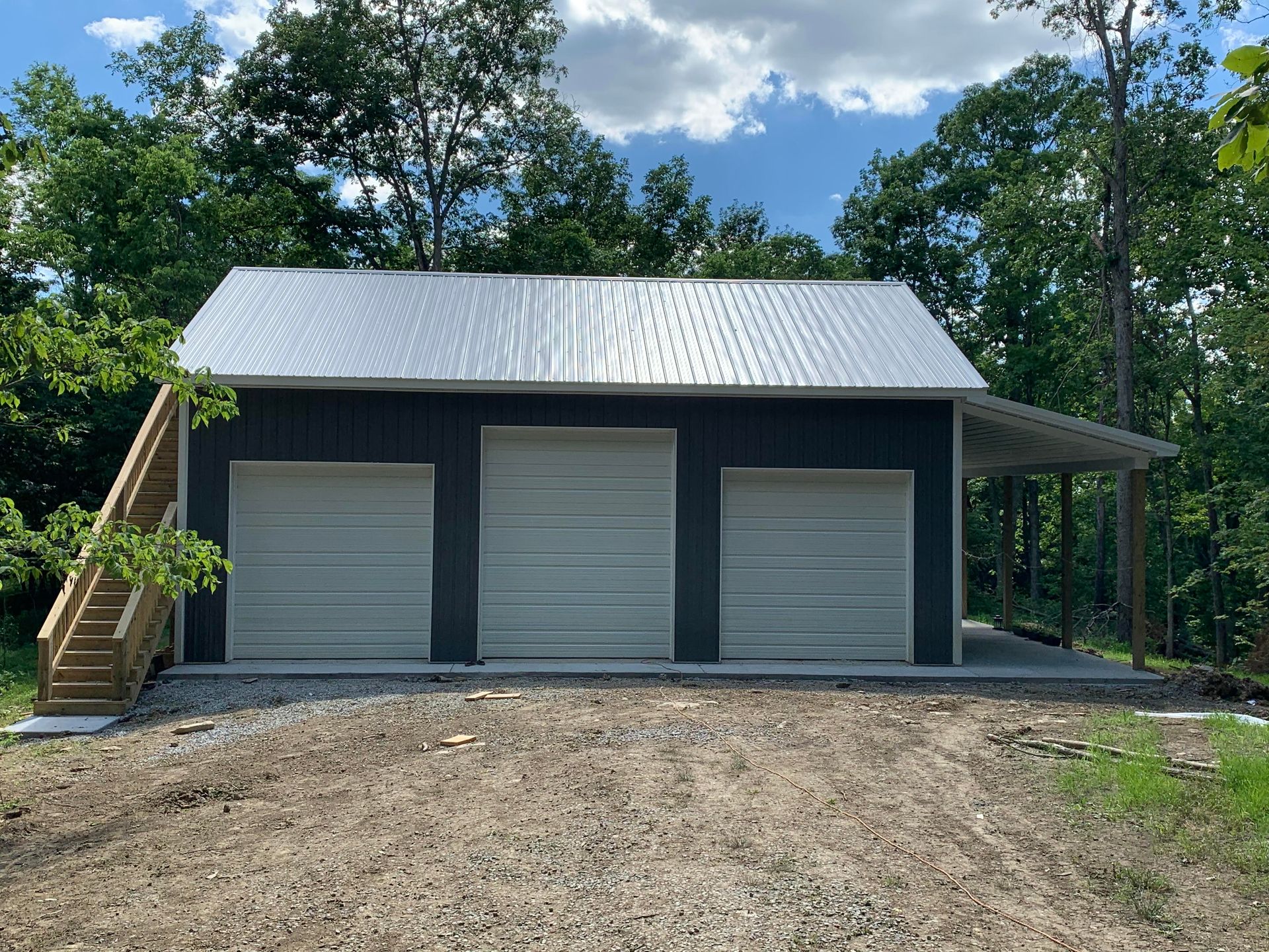 A blue garage is sitting in the middle of a grassy field.