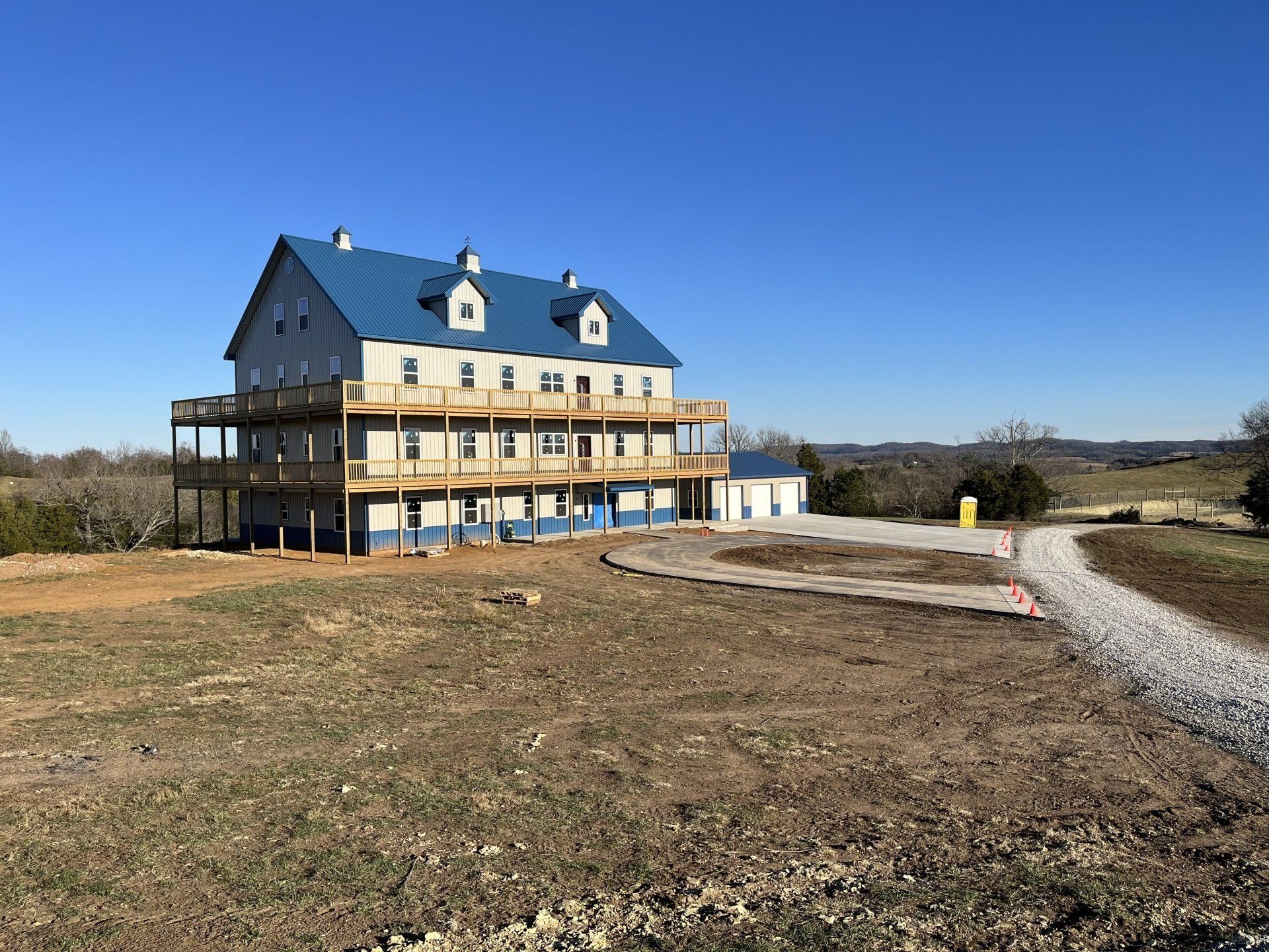 A purple house is sitting on top of a dirt hill surrounded by trees.