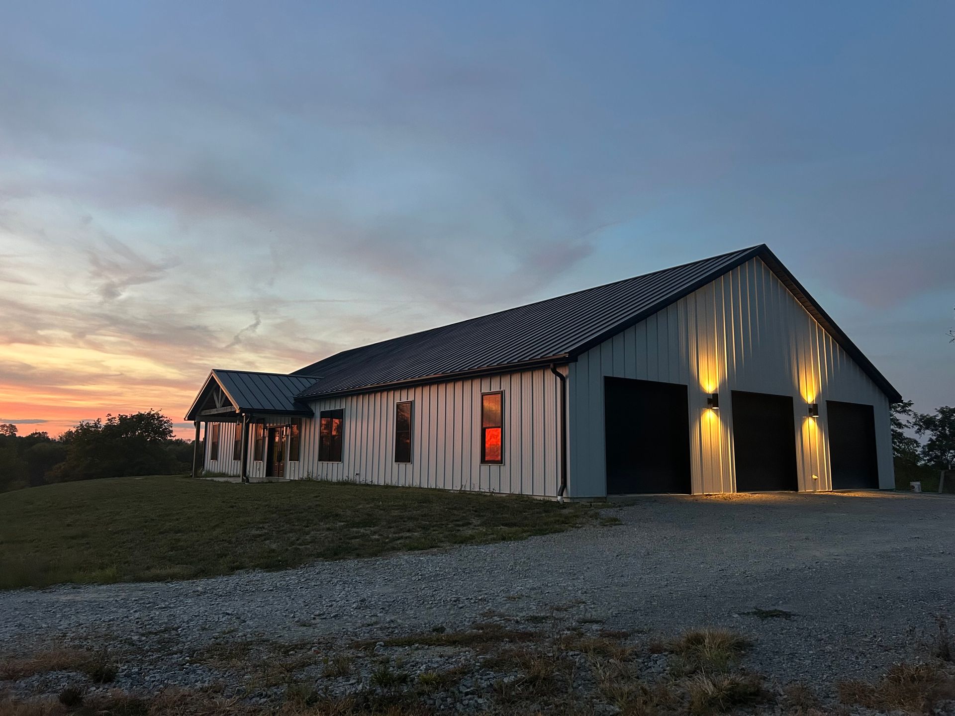 White house with a black metal roof and black window frames against a cloudy sky.
