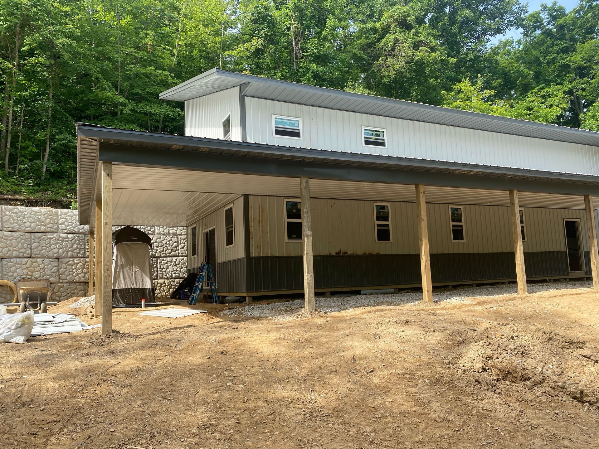 A two-story metal building with a covered porch. The exterior has light siding with a dark-colored bottom section and a dark roof.