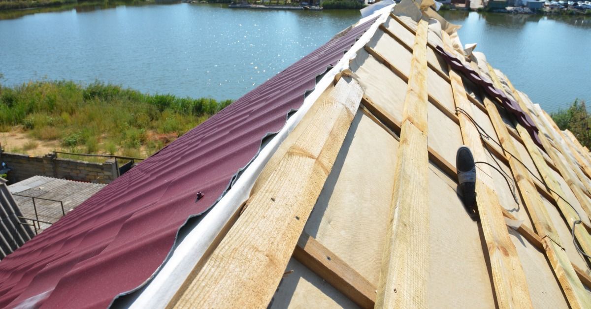 A close-up of a metal roof under construction with a moisture barrier installed beneath the roofing panels.
