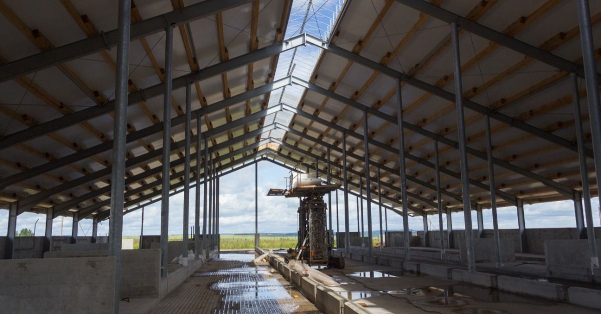 The interior of a large pole barn under construction shows metal framing, roof insulation, and open 
