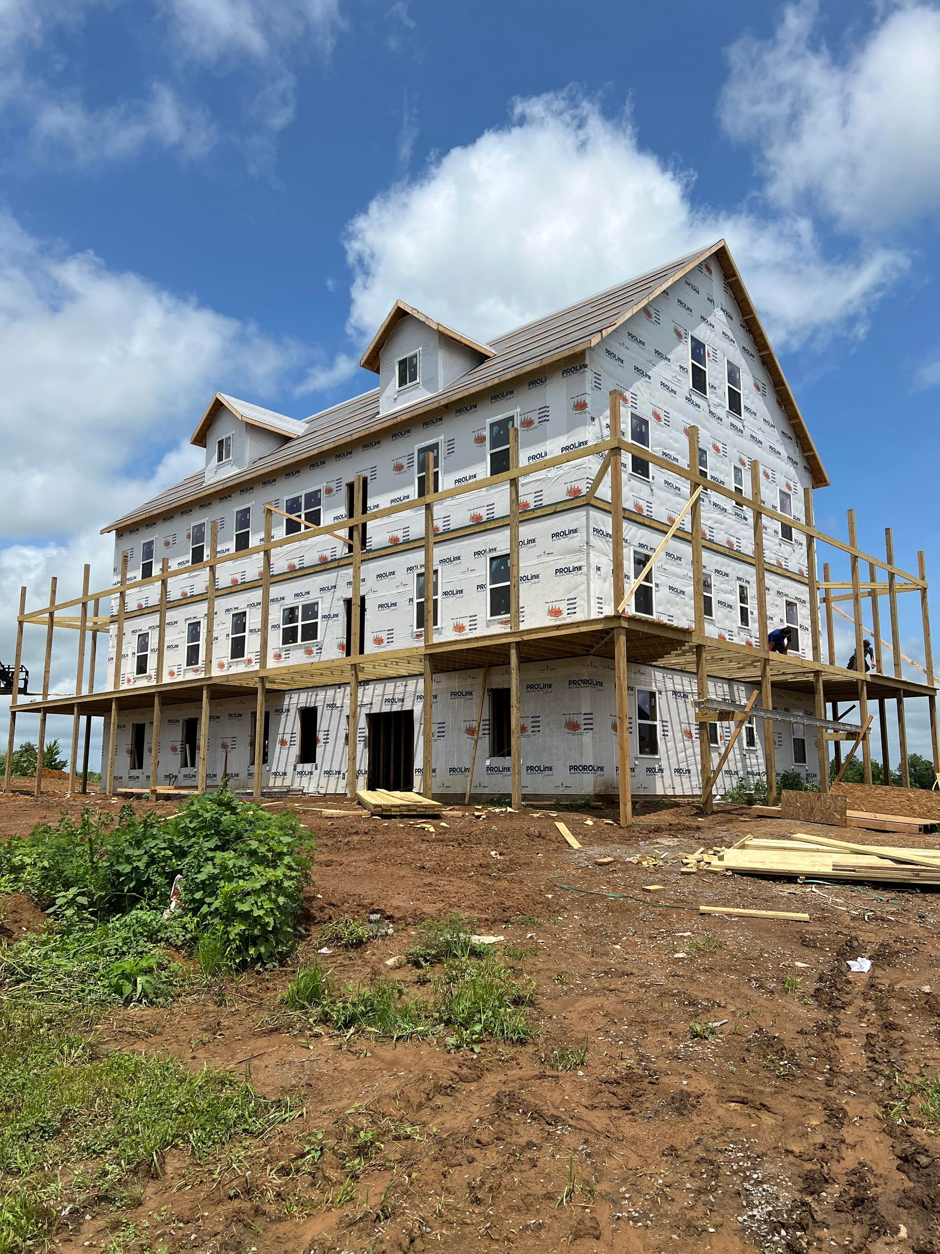 Building under construction, wrapped in white, with scaffolding and a blue sky backdrop.
