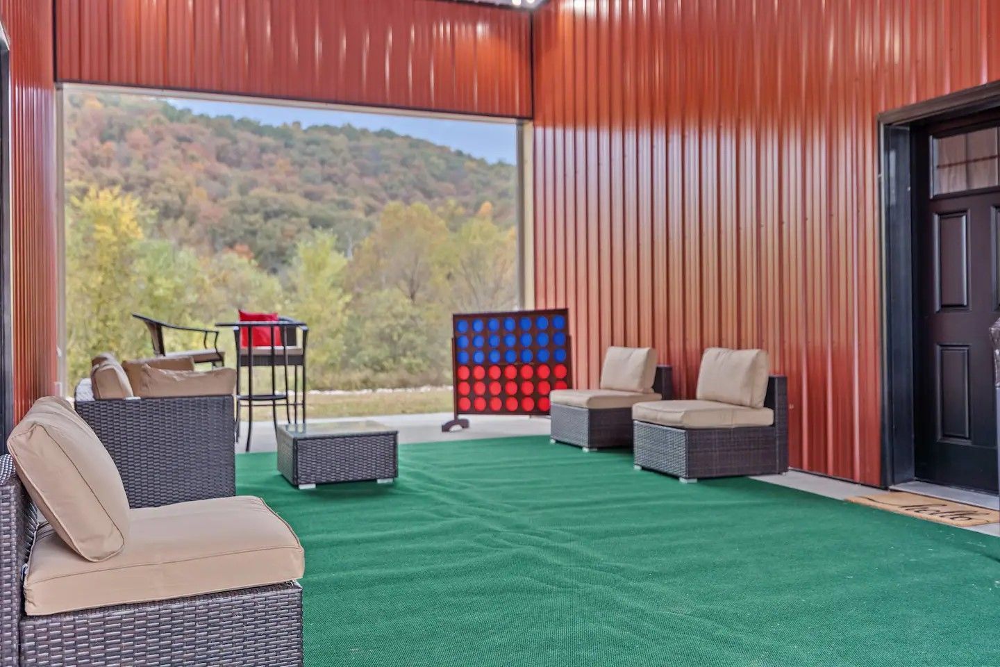Outdoor patio with green carpet, seating, and a view of trees and mountains. Includes a Connect Four game.