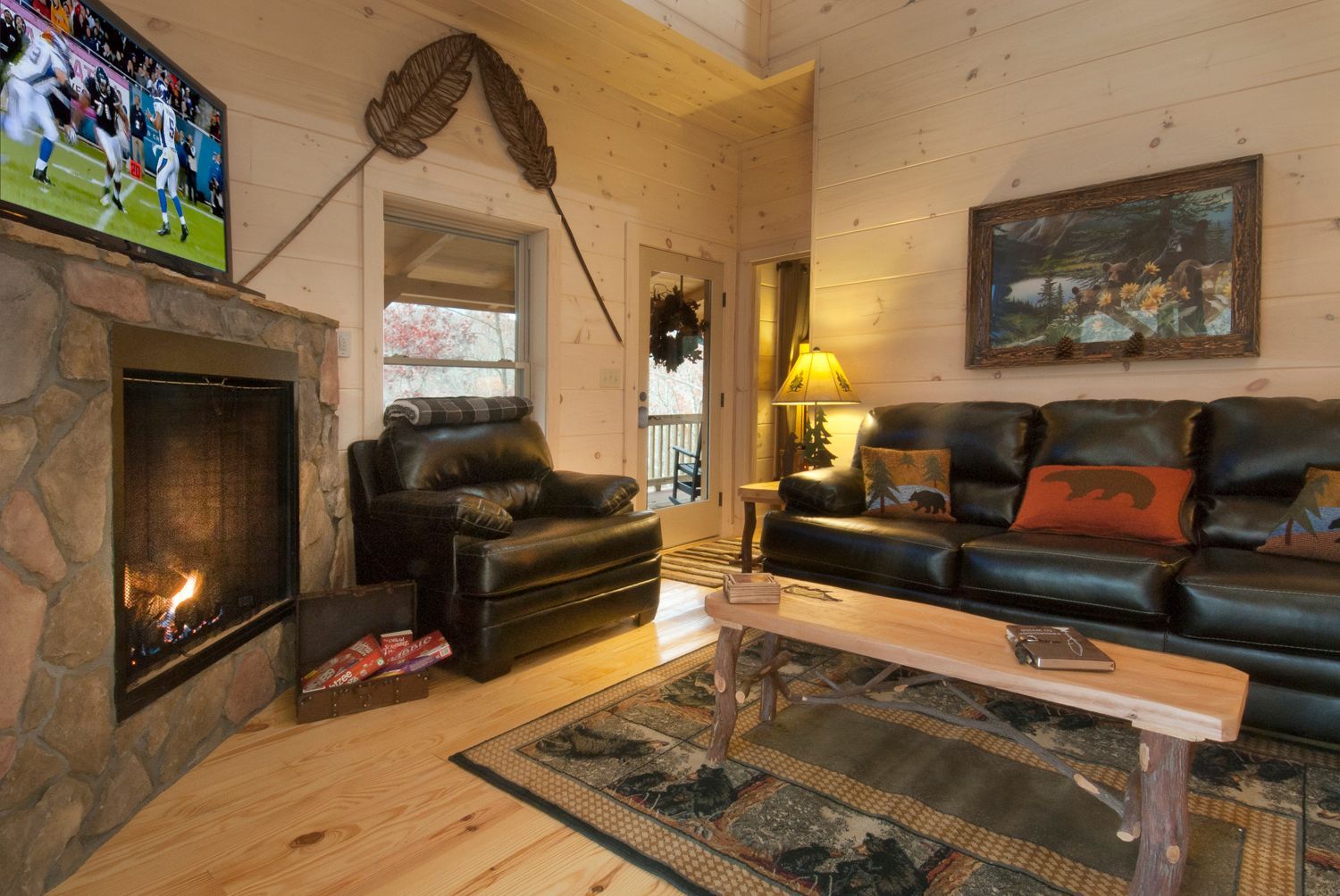Cozy cabin living room with fireplace, leather furniture, TV, and rustic decor.
