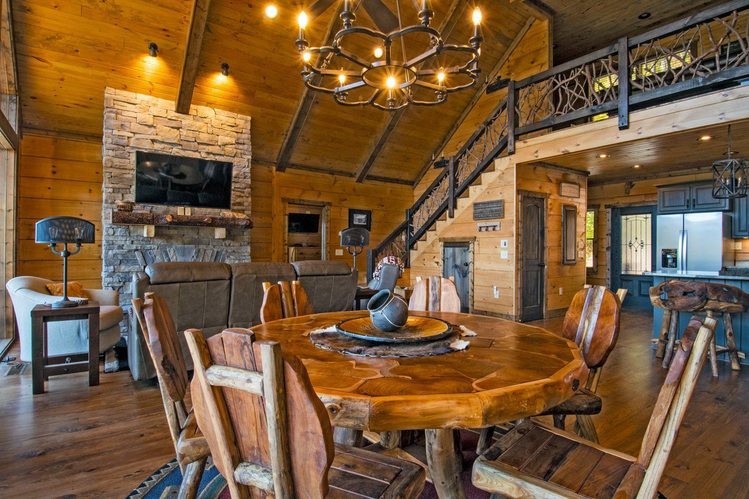 Rustic log cabin interior with dining area, fireplace, and loft.