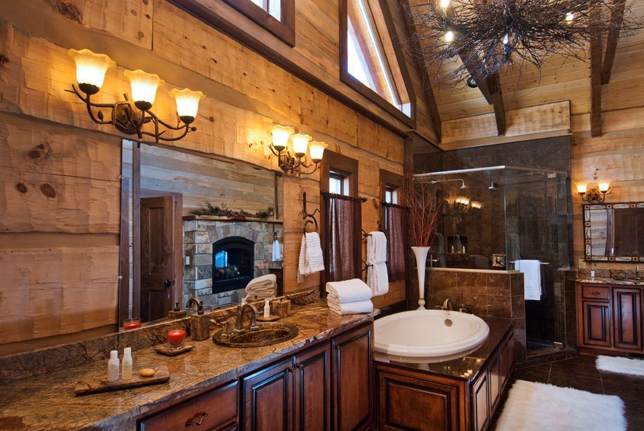 Rustic bathroom with wood paneling, granite countertop, fireplace reflection in mirror.