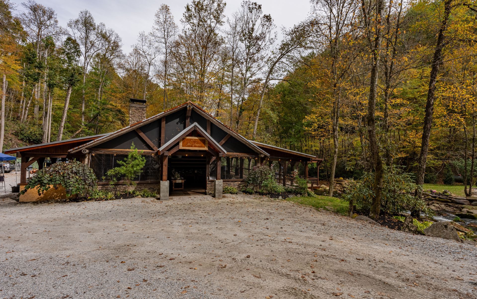 Covered porch with fireplace, barrel bar, string lights, and dining tables, wood and stone elements.