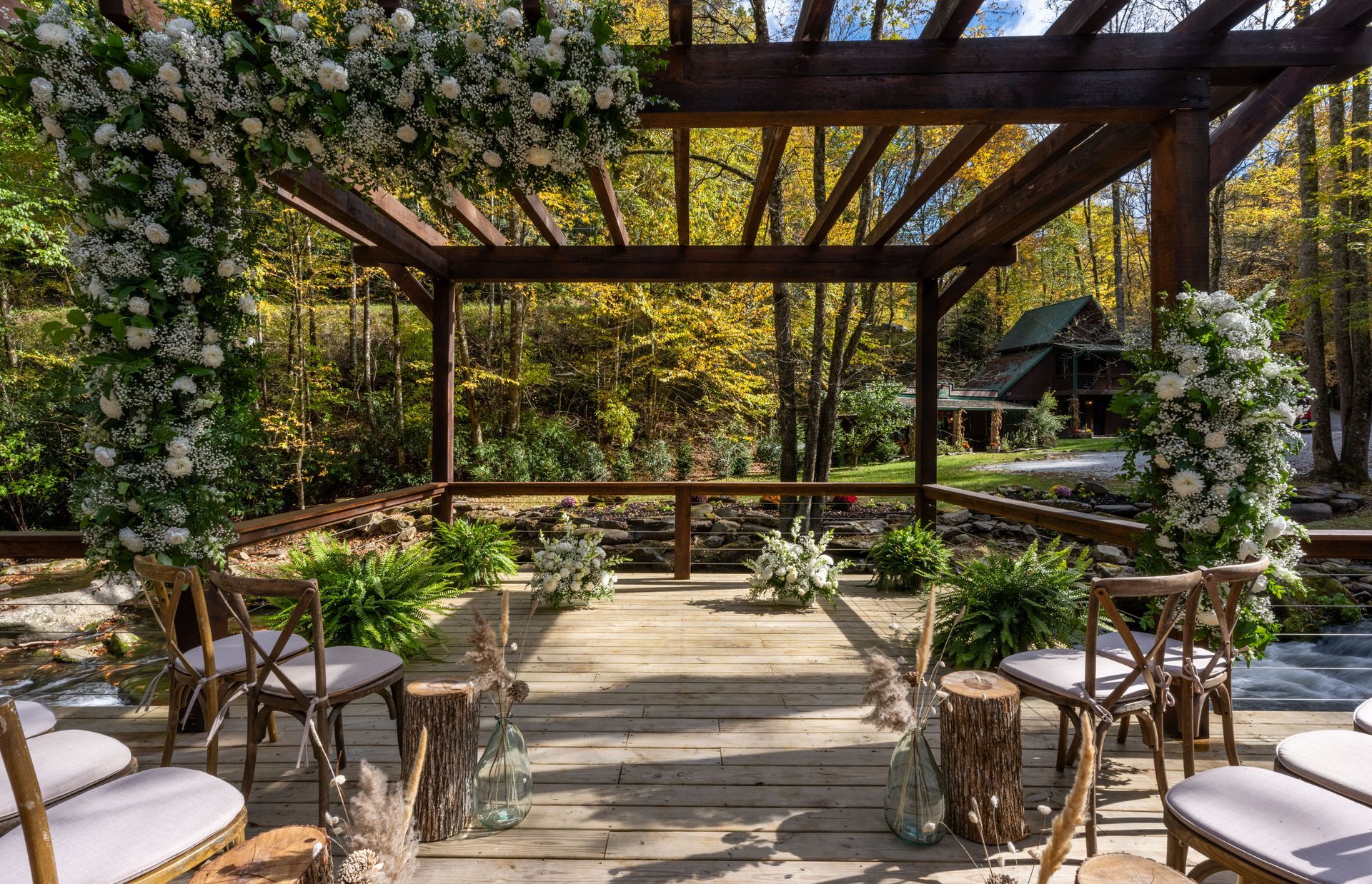 Wooden pergola decorated with flowers, prepared for an outdoor wedding ceremony in a forest.