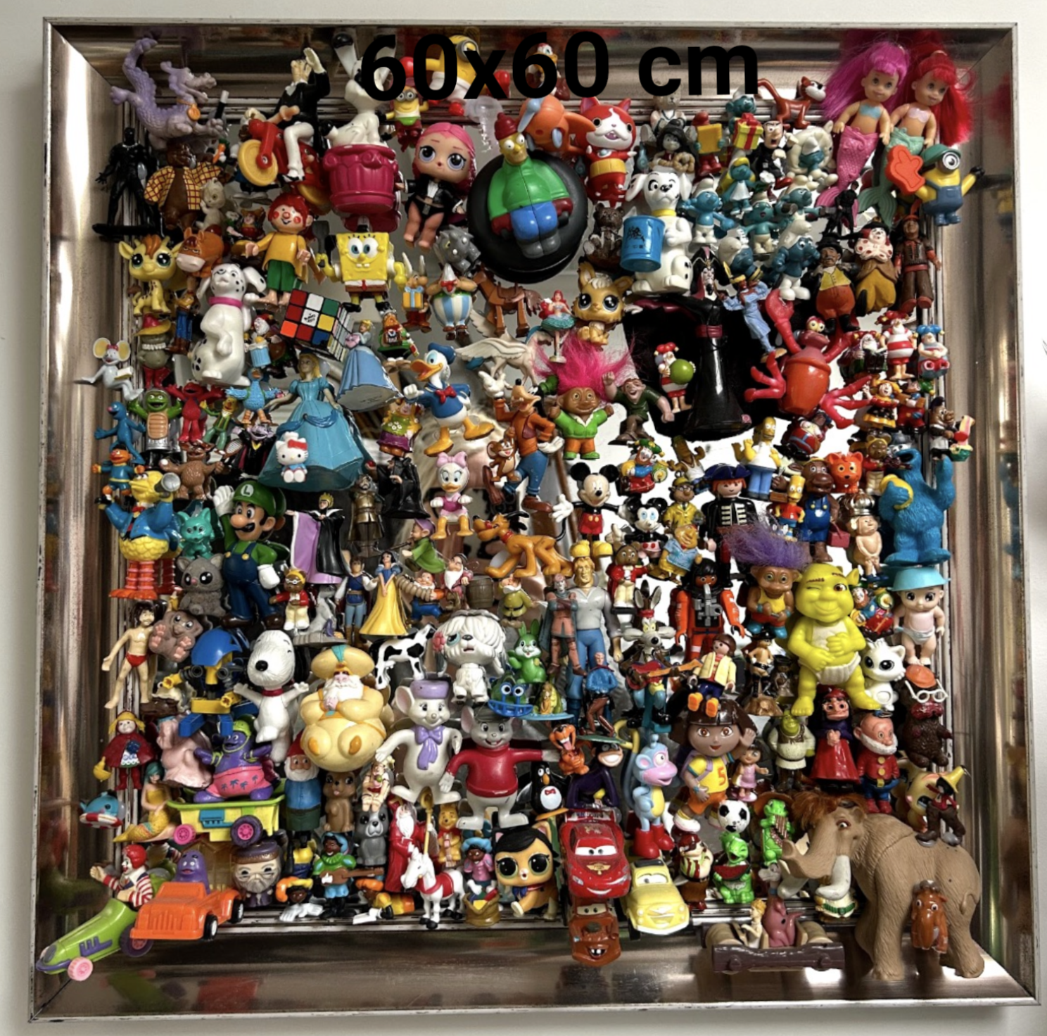 Een grote vierkante vitrinekast gevuld met een dichte verzameling kleurrijke kleine plastic beeldjes, poppen en speelgoedfiguren.