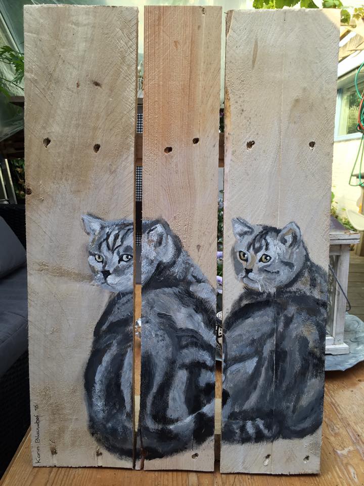 Twee grijze gestreepte katten geschilderd op drie verticale houten latten, waarbij één kat over zijn schouder achterom kijkt.
