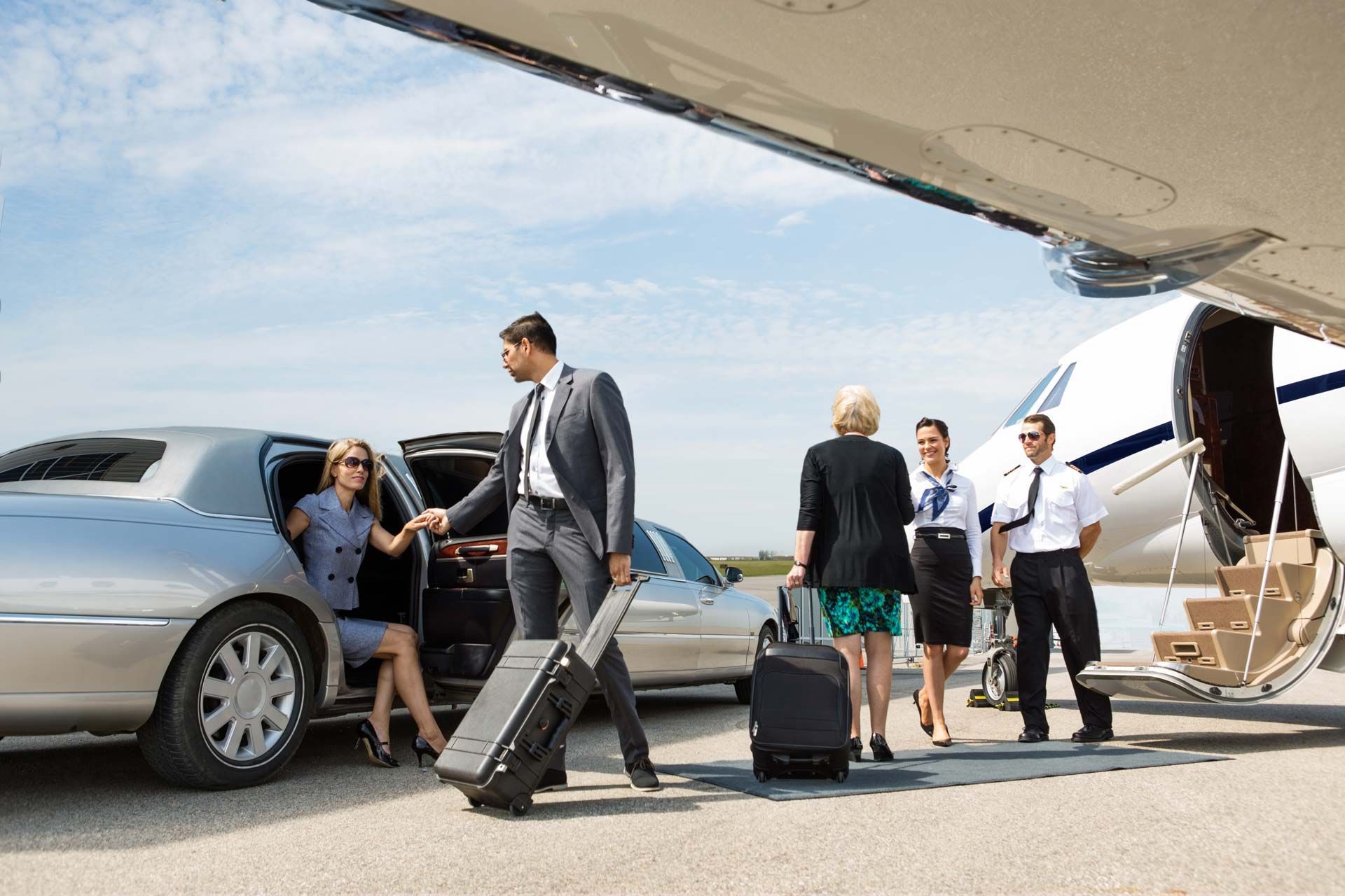 People exiting a limousine onto an airport tarmac, walking toward a private jet.