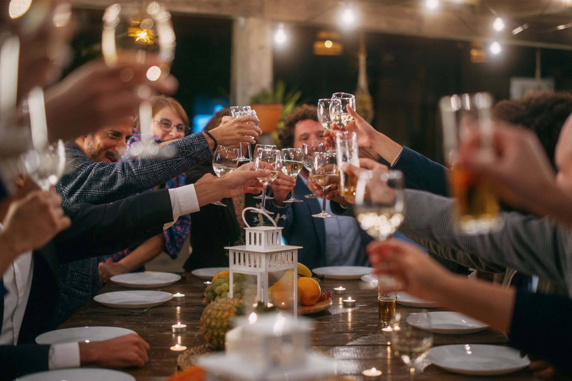 People clink glasses around a candlelit table.