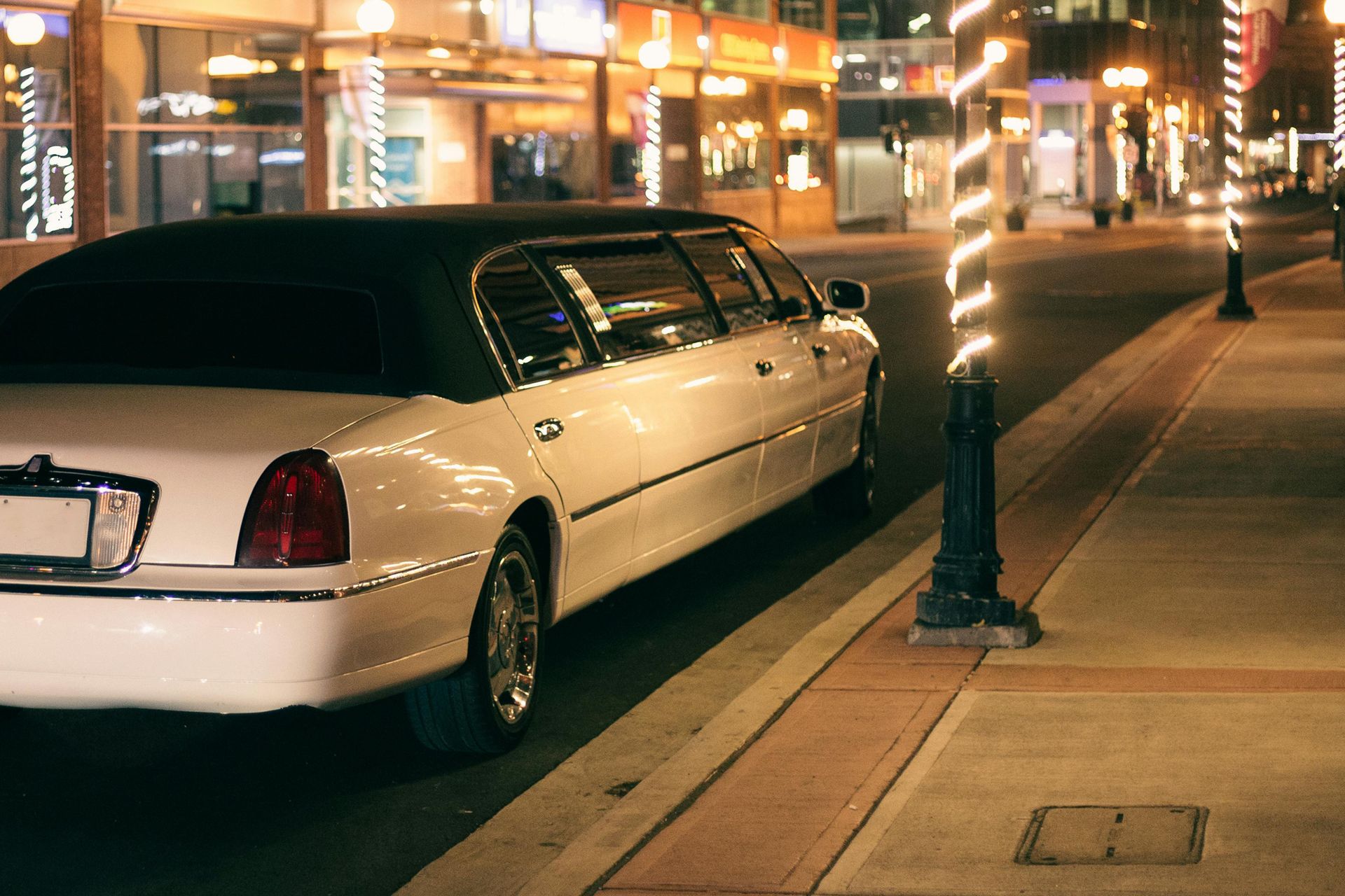White limousine parked on a city street at night.