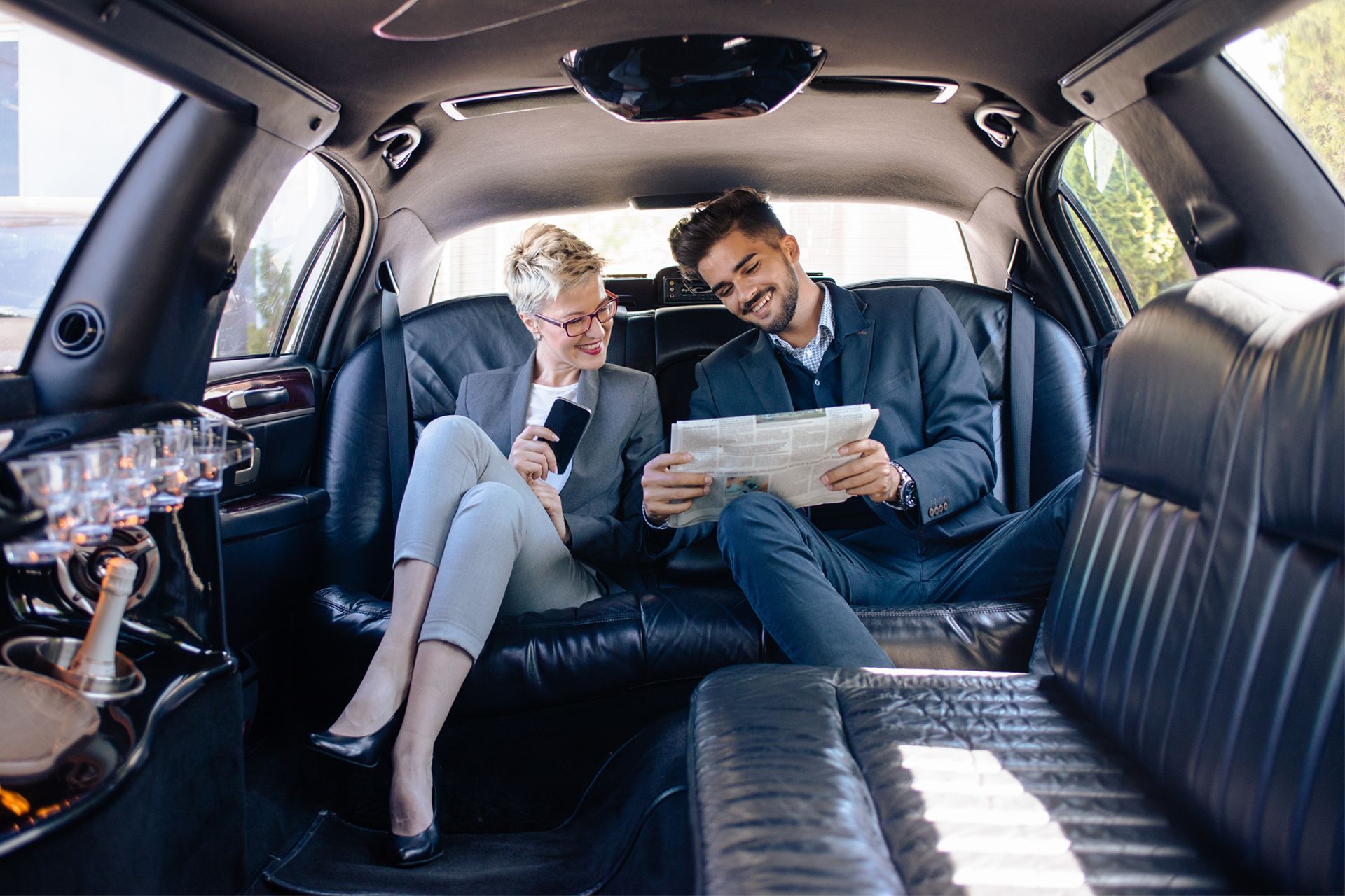 A man and a woman in business attire inside a limousine.