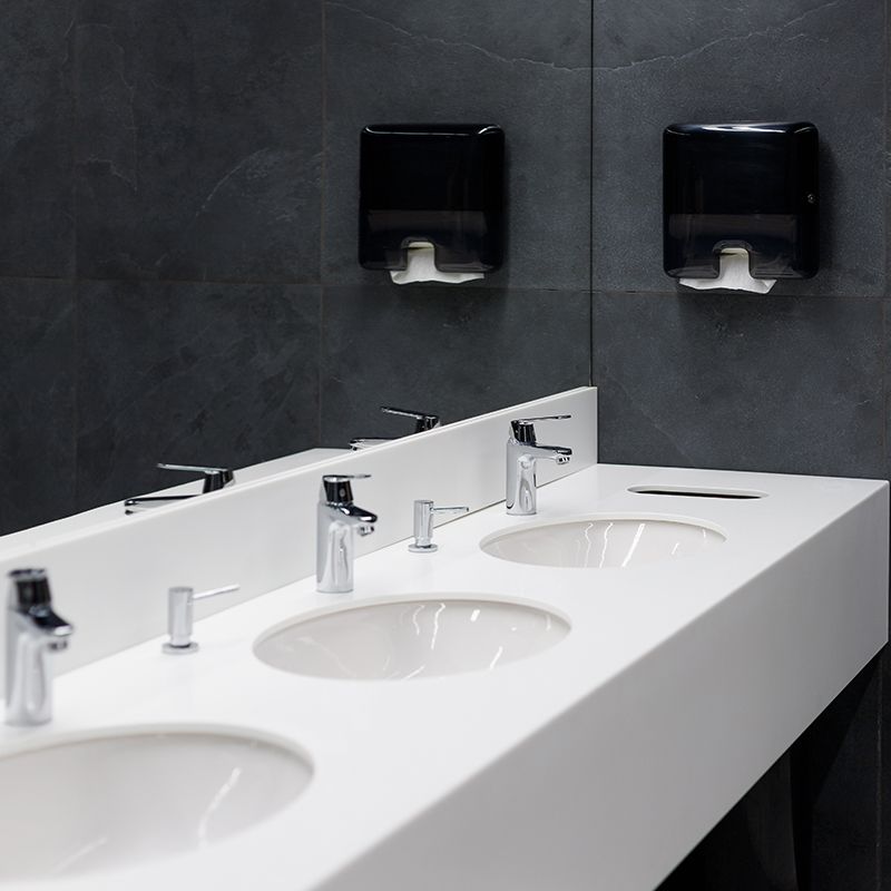A bathroom with three sinks and two paper towels dispensers