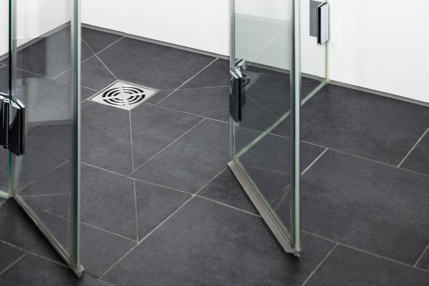 A bathroom with a black tile floor and a glass shower door