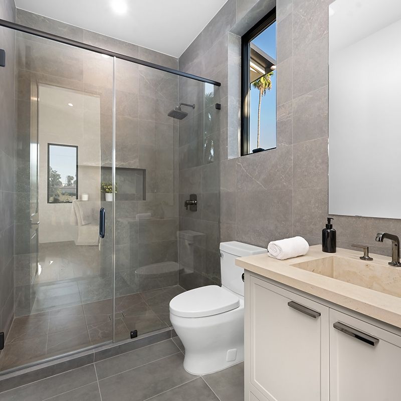 A bathroom with a toilet , sink and shower.