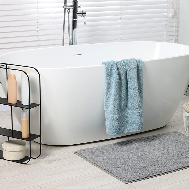 A bathroom with a bathtub and a towel on the side.