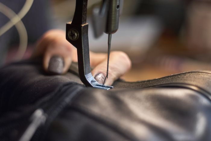 Tailor Sewing Leather Jacket with Sewing Machine — Mount Morris, MI — Superior Furs & Leather