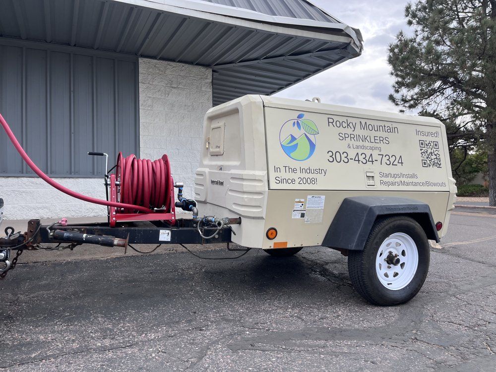 A trailer with a hose attached to it is parked in front of a building.