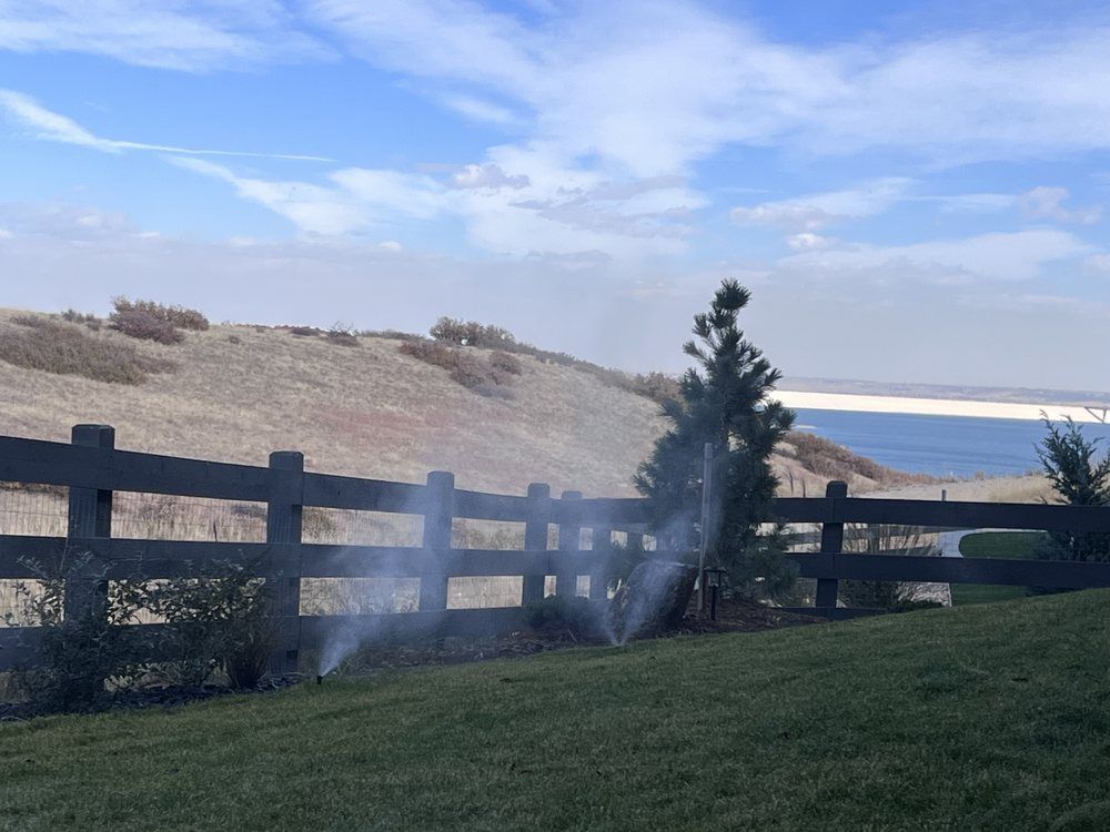 A wooden fence is surrounded by a lush green field