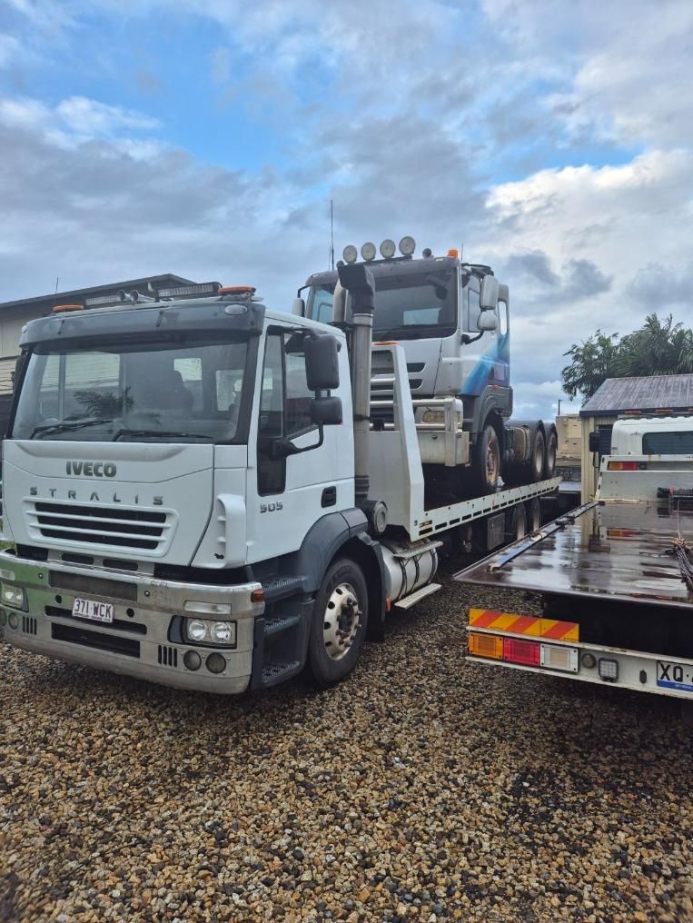 A Tow Truck is Carrying a Tractor on a Flatbed Trailer — Johnson River Towing In Innisfail, QLD