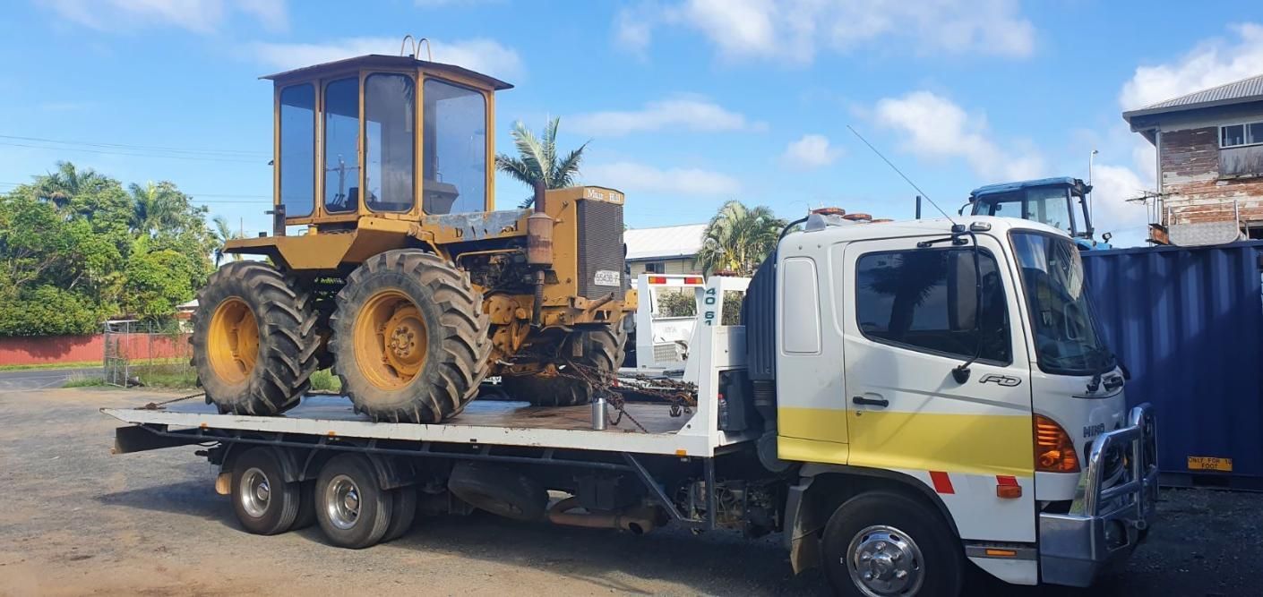 A Tow Truck is Carrying a Tractor on the Back of It — Johnson River Towing In Innisfail, QLD