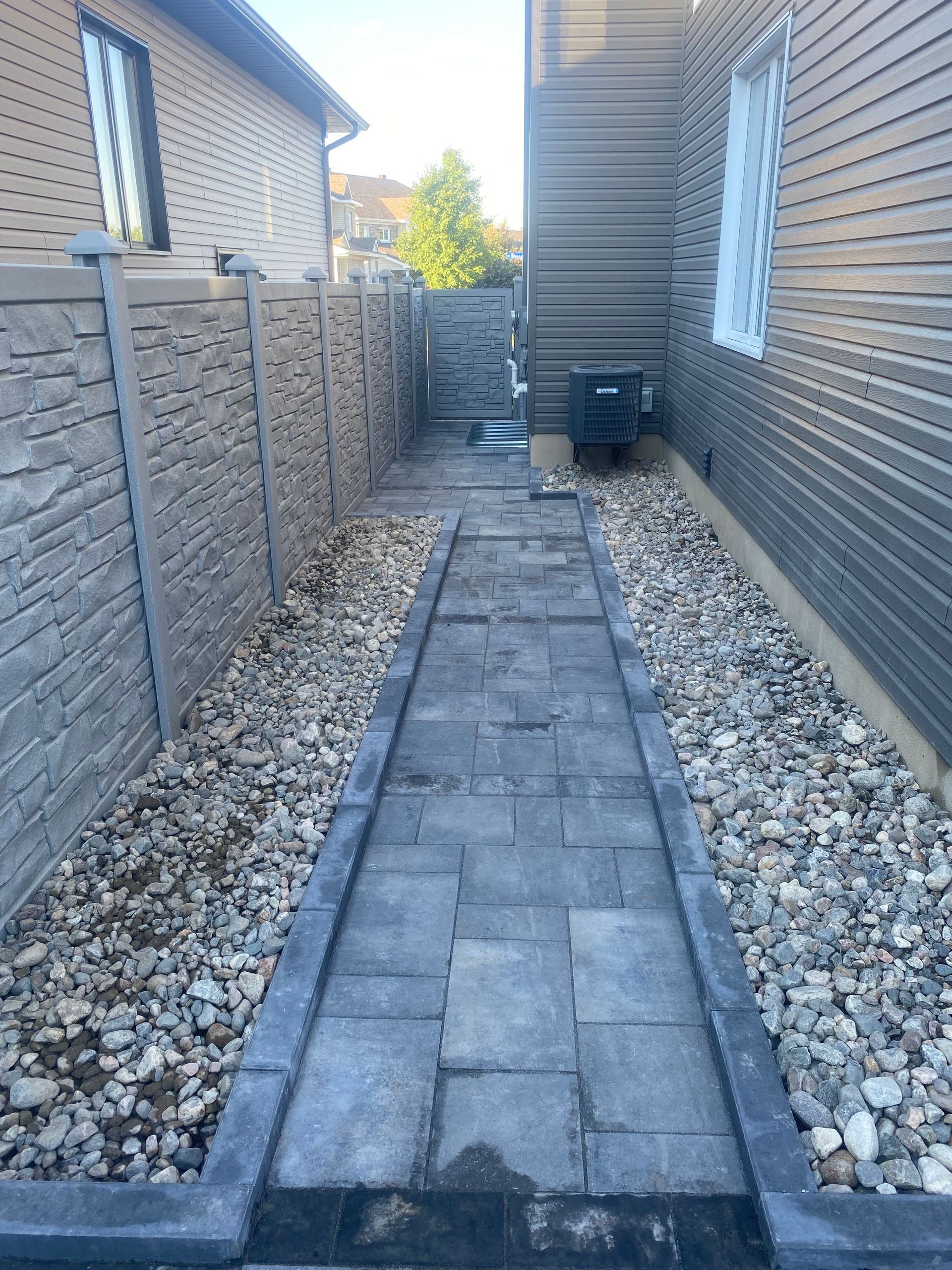 A stone walkway leading to a house with a stone fence.