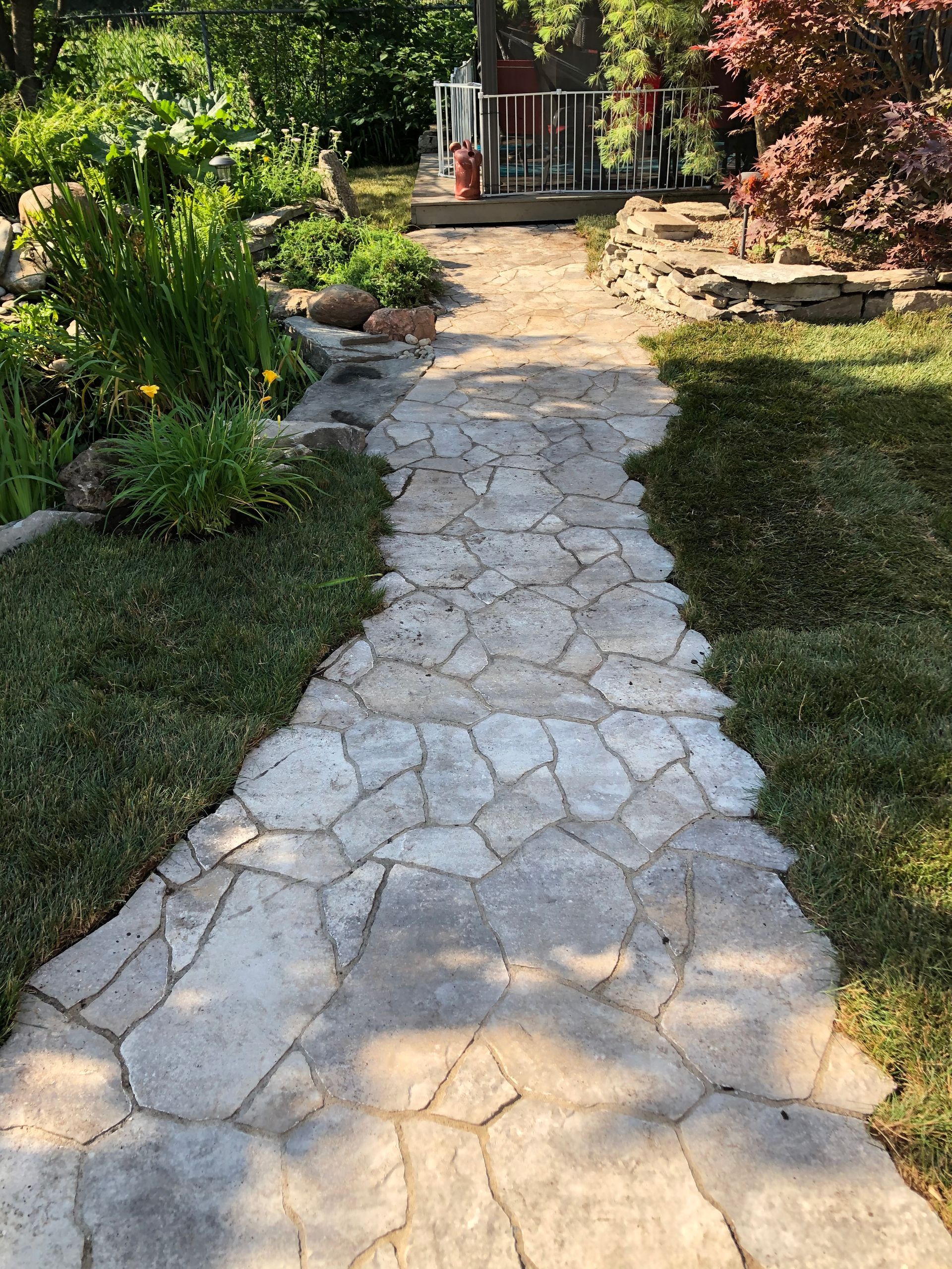 Une allée en pierre menant à une maison dans un jardin.