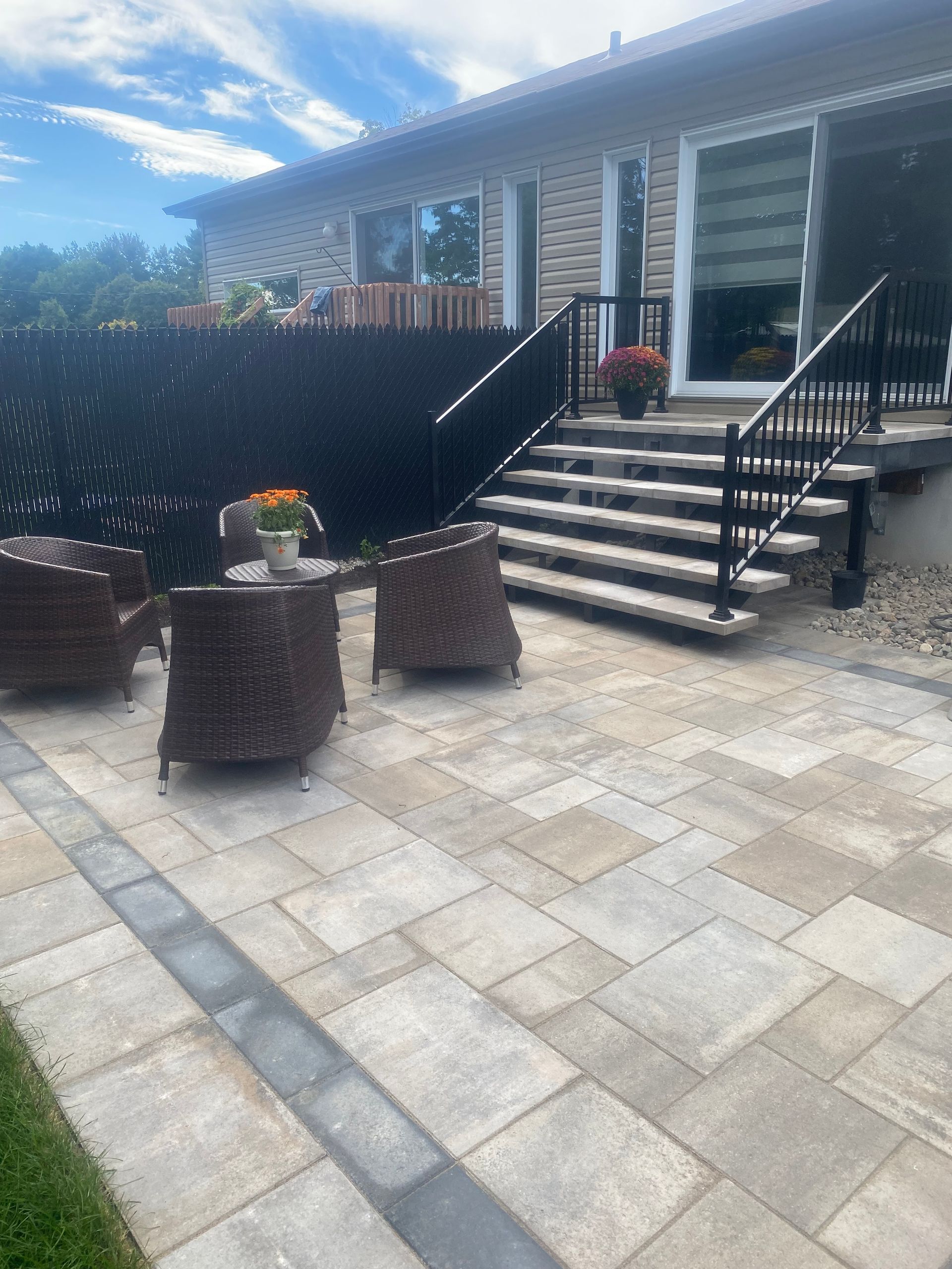 A patio with chairs and a table in front of a house.