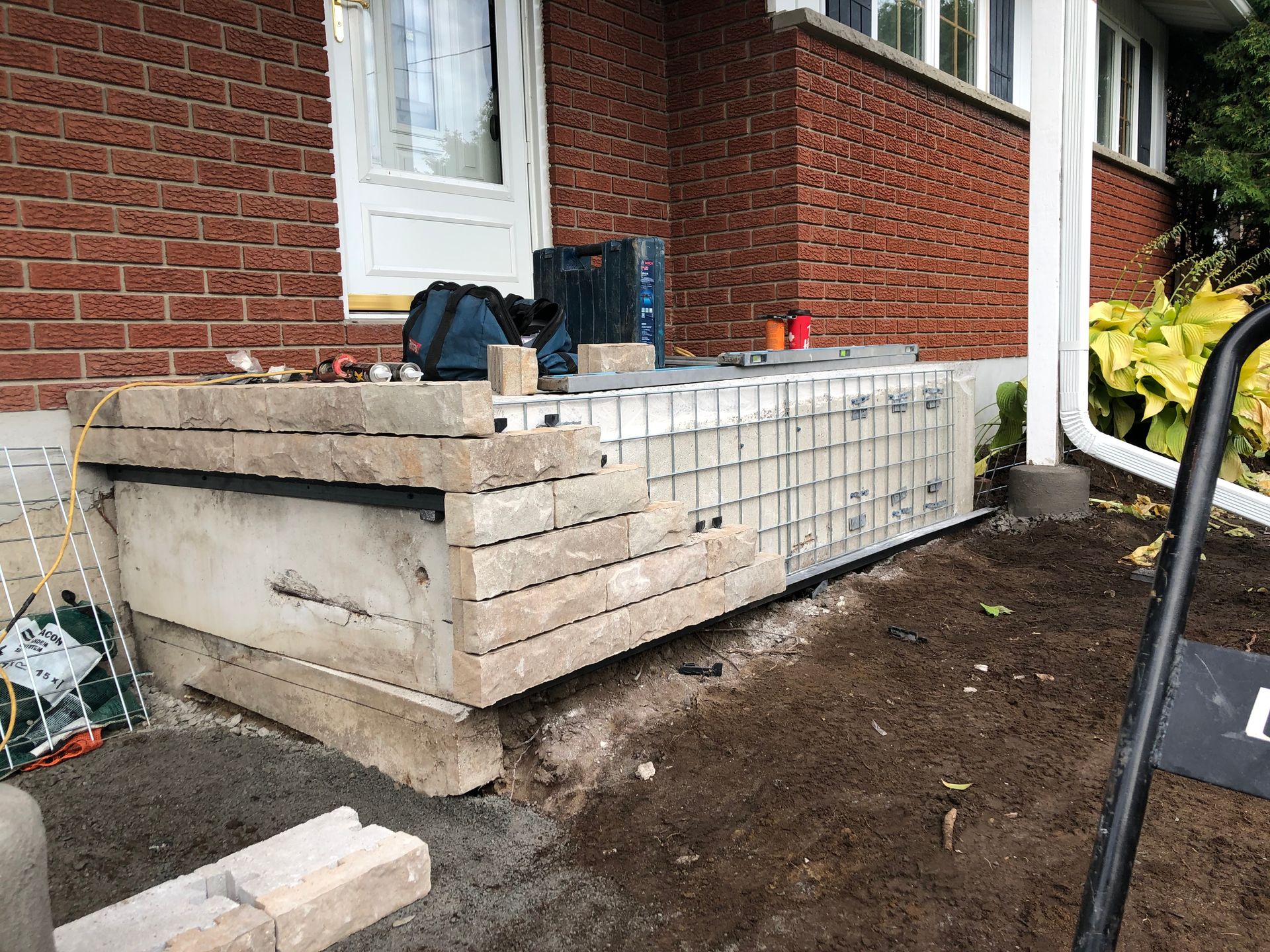 A brick house with a concrete staircase being built in front of it.