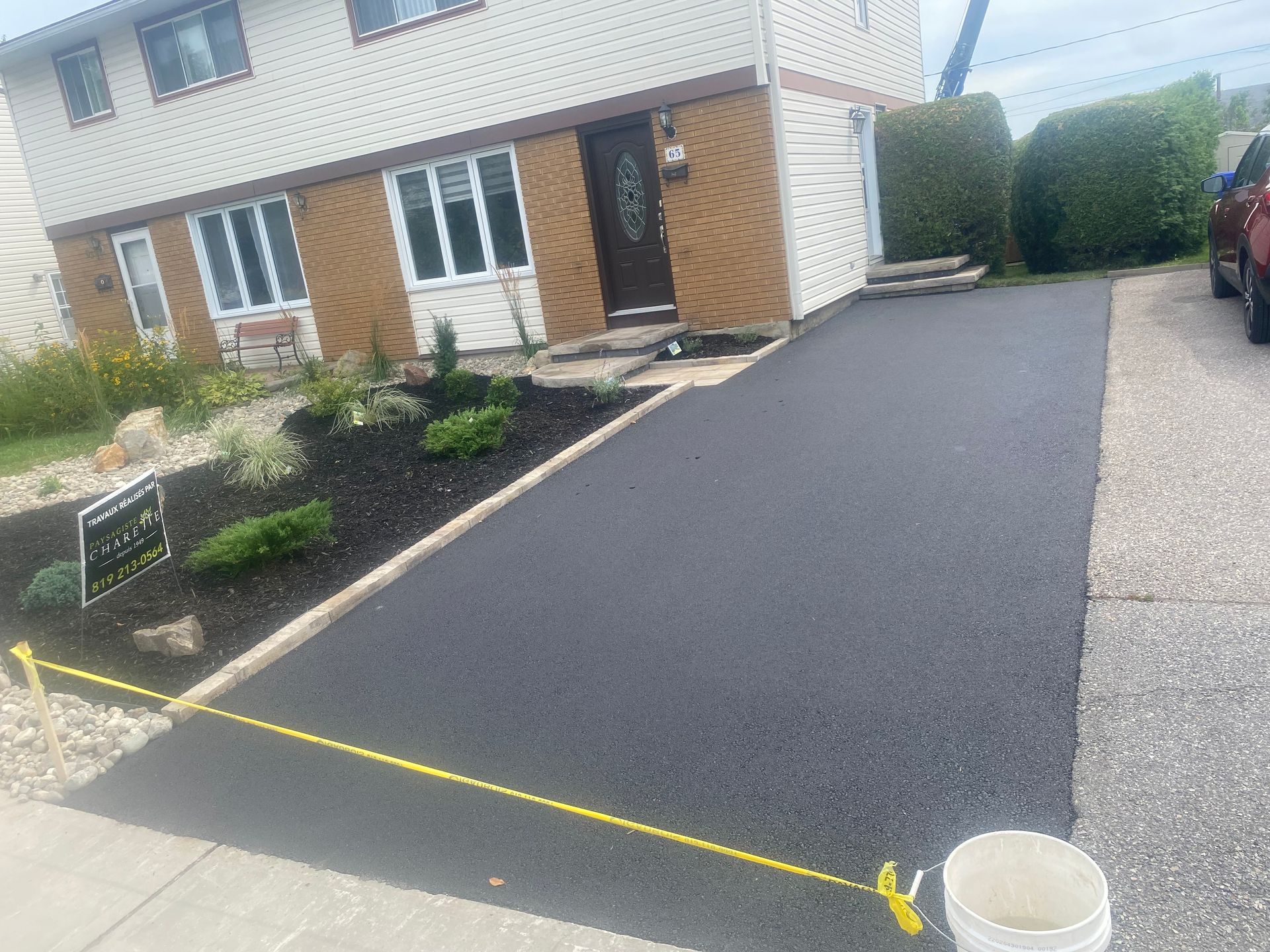 A house with a bucket of asphalt in front of it.