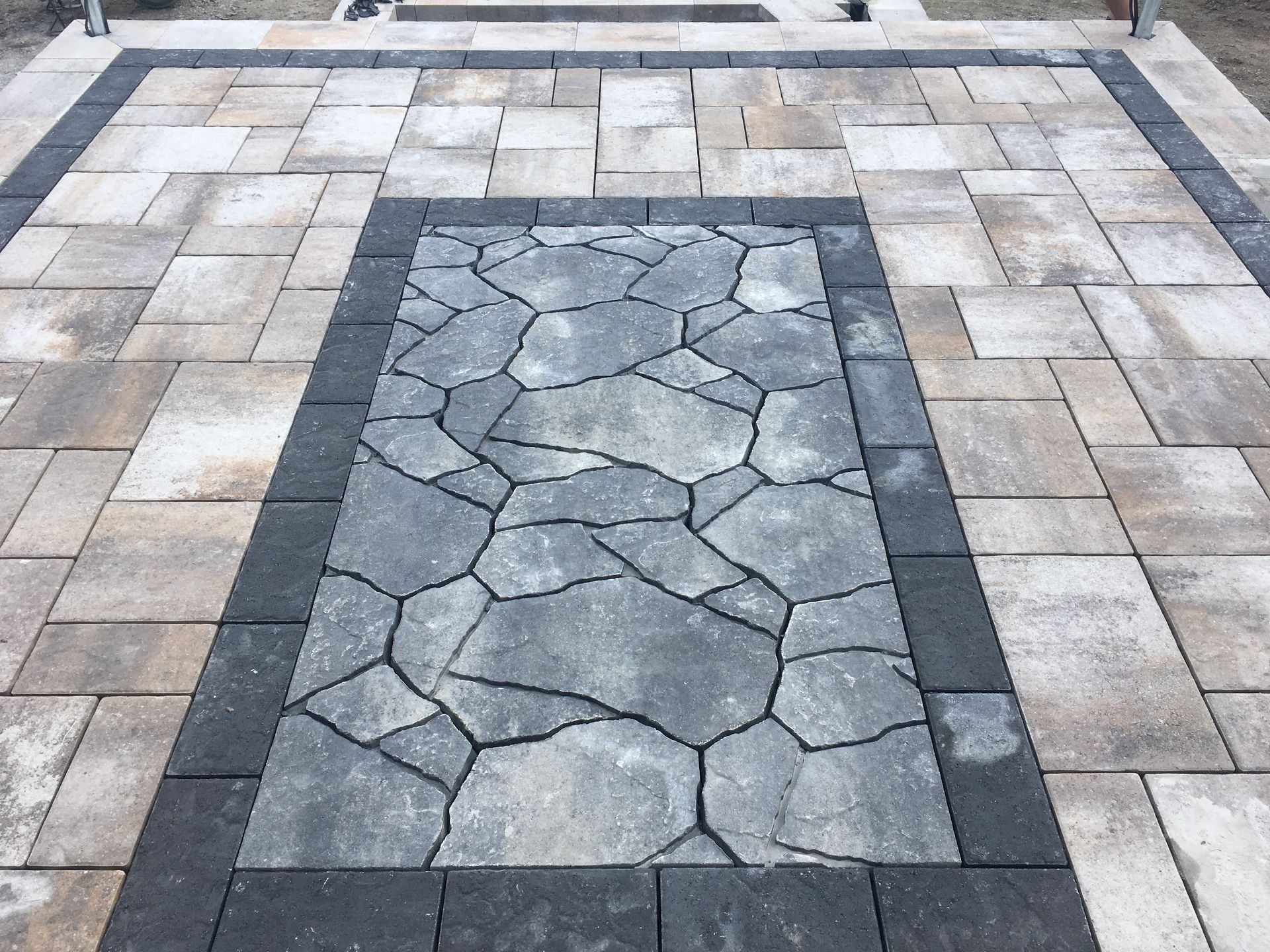 A patio with a stone border and a brick walkway