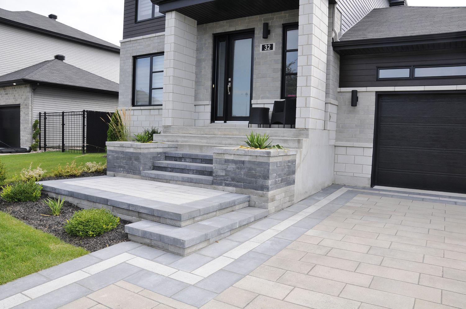 A house with a black garage door and steps leading up to the front door.