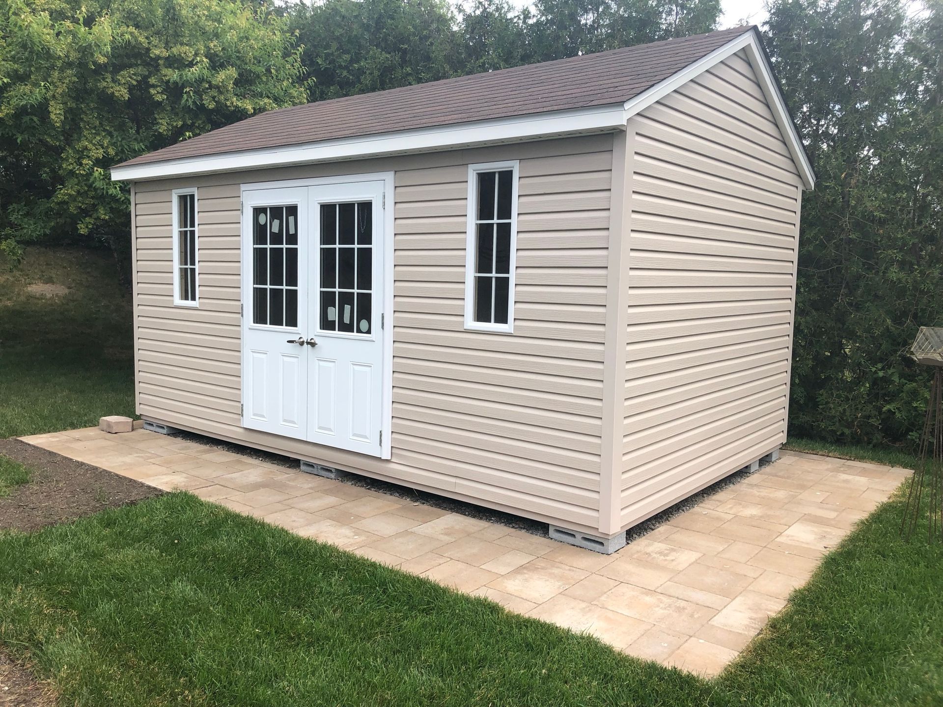 A small shed with a brown roof is sitting in the middle of a lush green field.